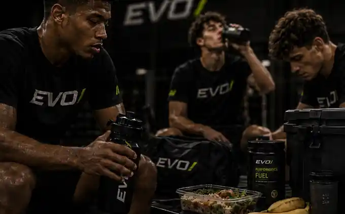 Athlete hydrating beside fresh fruit on a gym bench